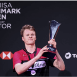 Anders Antonsen, in red and black shirt, holds the trophy after winning the men's singles final. Andersen, Wang win 2024 Denmark Open